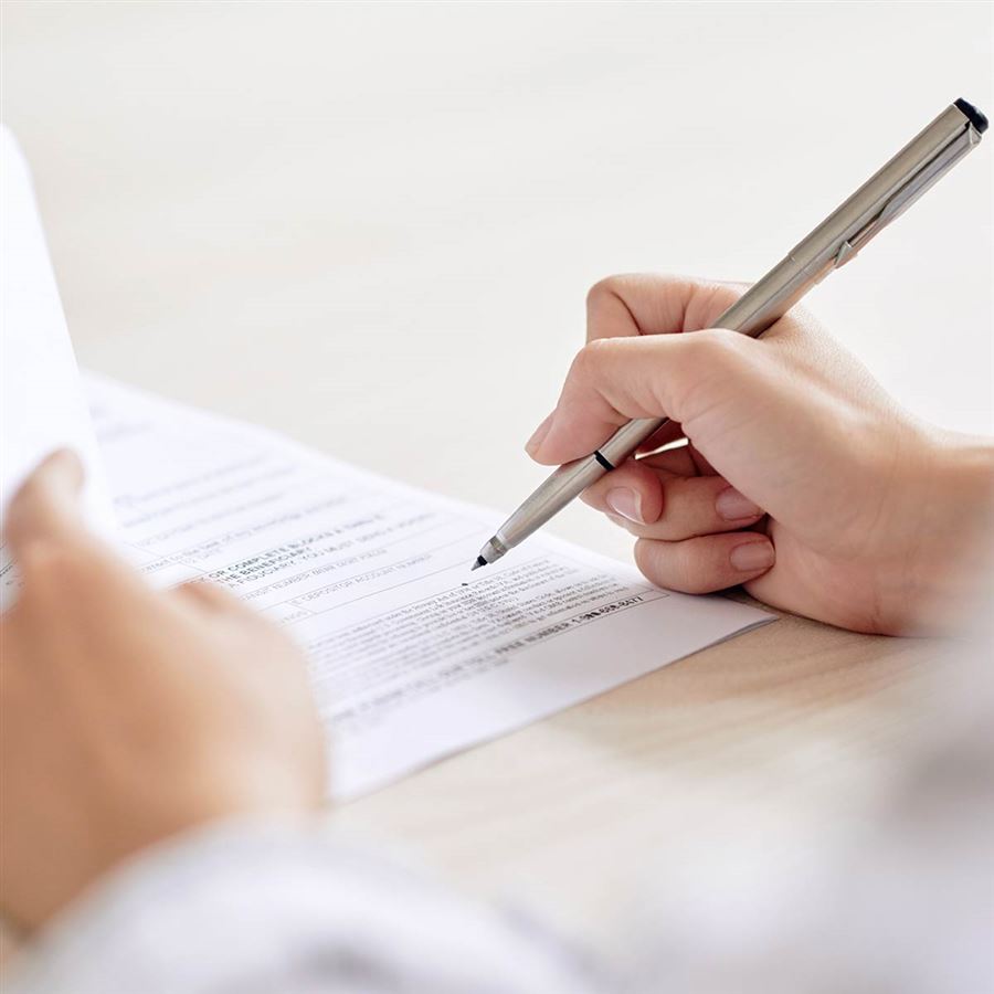 Pen in hand, signing documents. 