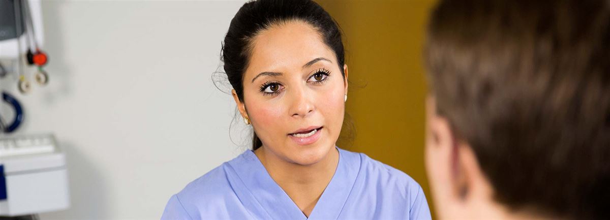 Kvinnlig läkare talar till patient.