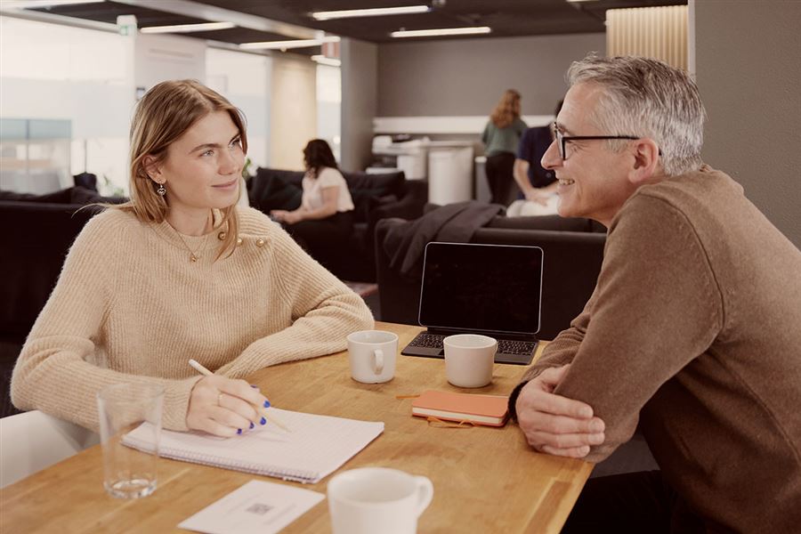A woman and a man are sitting down in an office. They are discussing a job-related issue. 