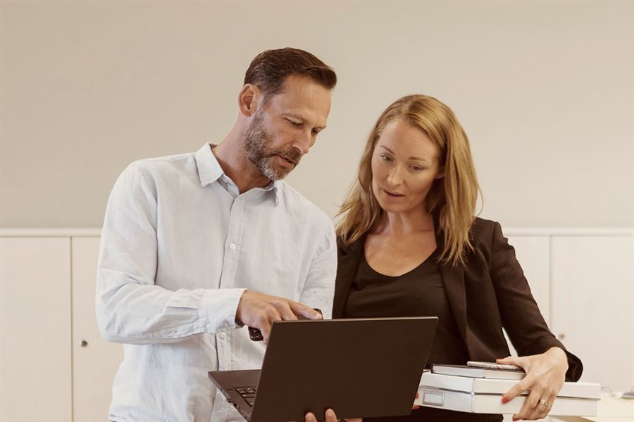 A man and a woman are looking at a computer screen in the office.