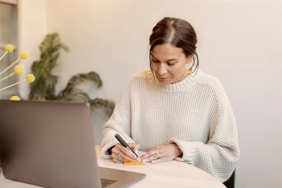 Woman sitting at a table looking at a computer. 