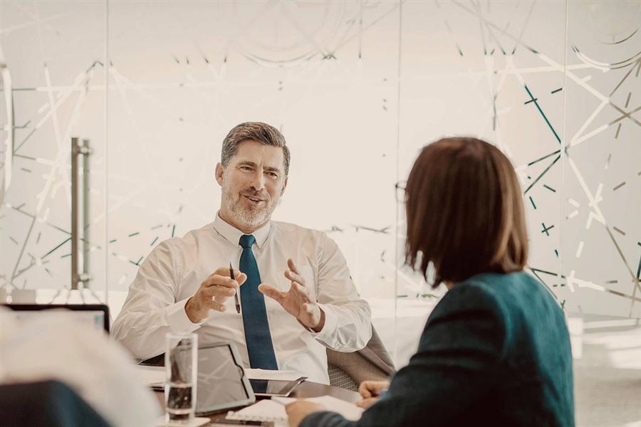 A man is sitting down at a table with his team to discuss a business plan.