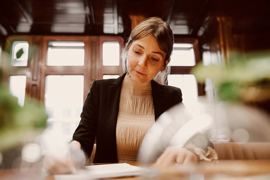A business woman is sitting at a table, looking at some papers.