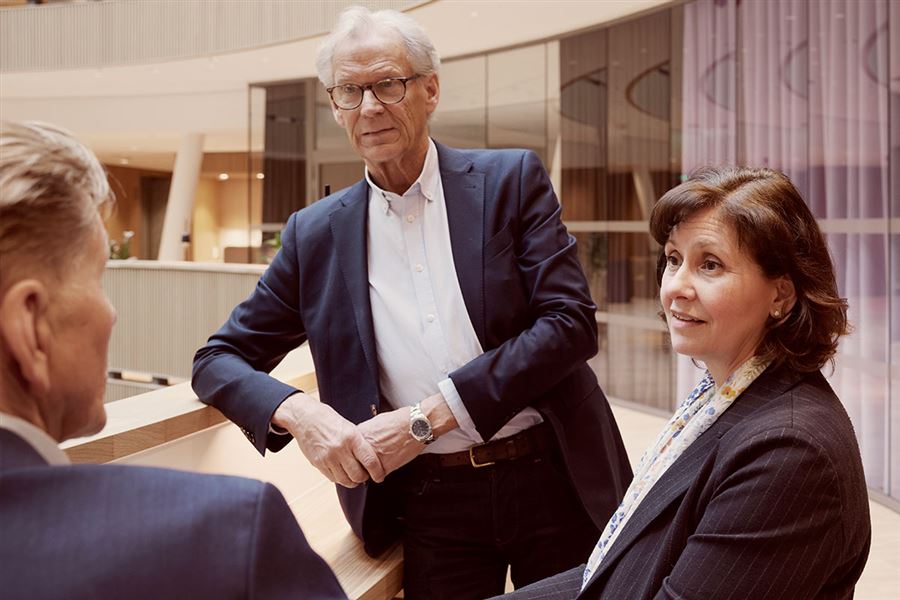 Aktieägare står och diskuterar affärer i ett mötesrum. 
